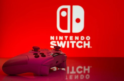Dhaka, Bangladesh- 15 July 2025: Smartphone with nintendo switch logo, game controller, and earbuds