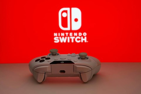 Dhaka, Bangladesh- 15 July 2025: Smartphone with nintendo switch logo, game controller, and earbuds