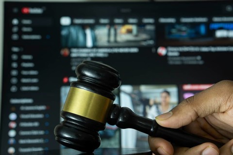 Dhaka, Bangladesh- 20 June 2025: A hand holds a gavel in front of a computer screen displaying