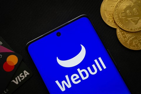 Dhaka, Bangladesh- 26 Aug 2025: Smartphone displaying webull logo surrounded by Bitcoin coins and