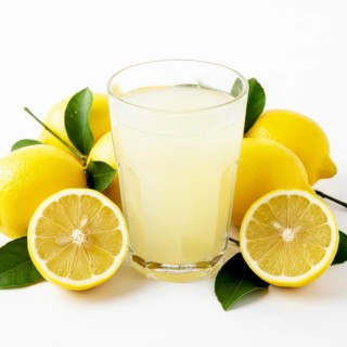 A vibrant image showcasing a glass of freshly squeezed lemonade surrounded by ripe lemons and green