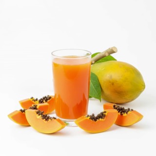 A refreshing glass of papaya juice is surrounded by fresh papaya slices and a whole papaya fruit,
