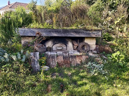 An old stone oven embedded in nature with surrounding plants and a rustic atmosphere, Weinviertel