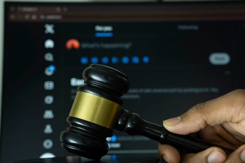 Dhaka, Bangladesh- 20 June 2025: A hand holds a gavel in front of a computer screen displaying X
