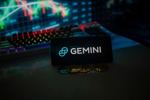 GEMINI logo set against market charts and coins, illuminated by colorful neon lights