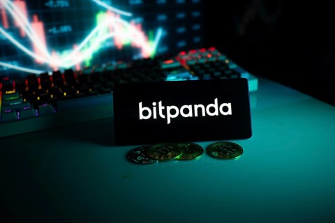 Bitpanda display with coins set against a stock chart with a turquoise neon glow