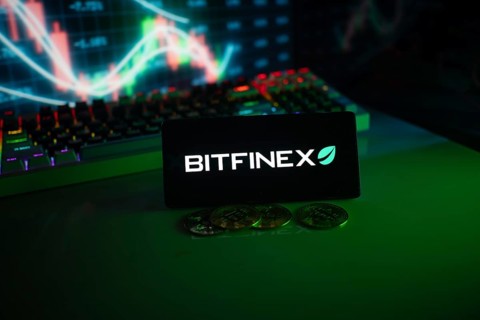 Bitfinex screen with coins in front of a stock chart illuminated by green neon lights