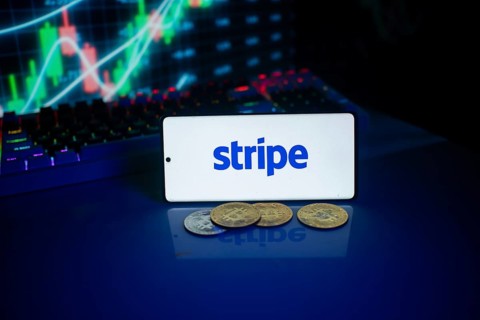 Phone with Stripe logo beside coins and market chart, implying financial transactions