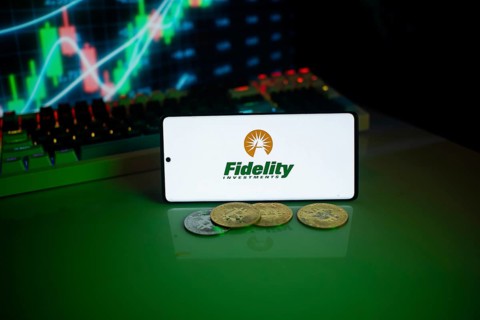 Phone displaying Fidelity Investments next to coins, with a financial market background