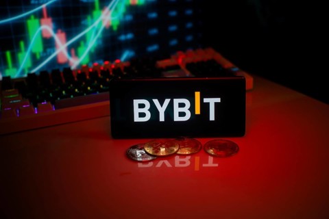 BYBIT logo on phone with a red glow, coins, and stock chart, suggesting a trading focus
