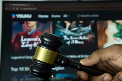 Dhaka, Bangladesh- 20 June 2025: A hand holds a gavel in front of a computer screen displaying