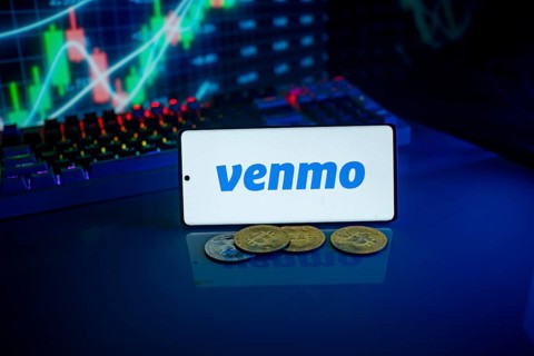 Phone displaying Venmo logo with coins and a backlit keyboard, signifying digital payments and