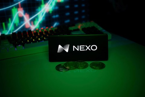 NEXO on a smartphone with currency tokens and fluctuating charts behind