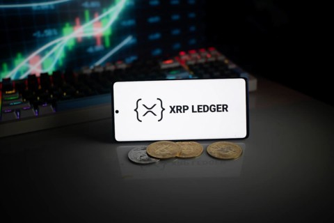 Phone displays XRP Ledger logo with crypto coins and trading graphics visible