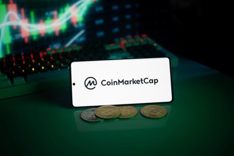 CoinMarketCap logo with coins and a glowing chart in a dim setting