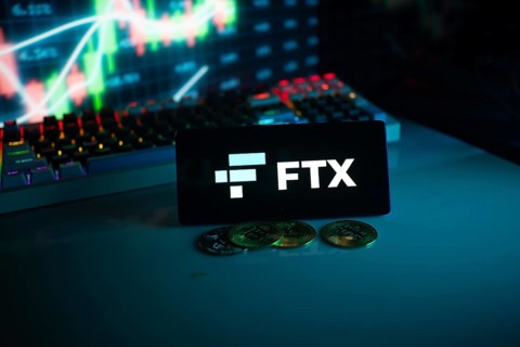 FTX logo on a screen in a dark setting with a glowing chart and coins