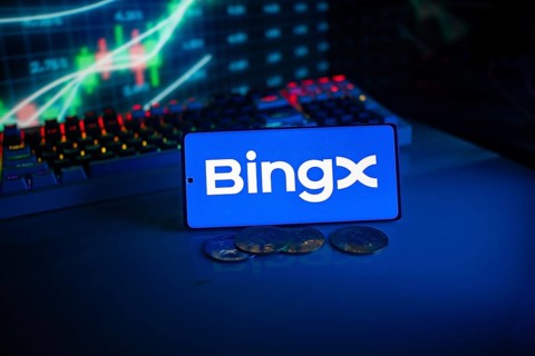Bingx logo on a phone with digital currencies and financial charts in the background