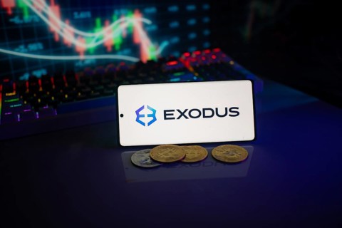 Exodus logo on a smartphone amid digital currencies and trading market charts