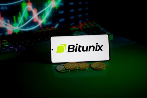 Bitunix logo on a phone with cryptocurrencies and market trend charts in the background