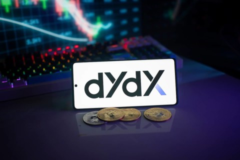 Dydx logo displayed on a phone with digital currencies and trading charts in the background
