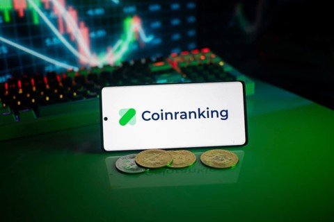Coinranking logo on smartphone with coins, green neon lights, and trading charts in background