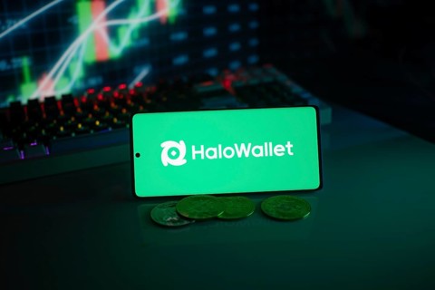 HaloWallet logo on smartphone with coins, green neon lights, and trading charts in background