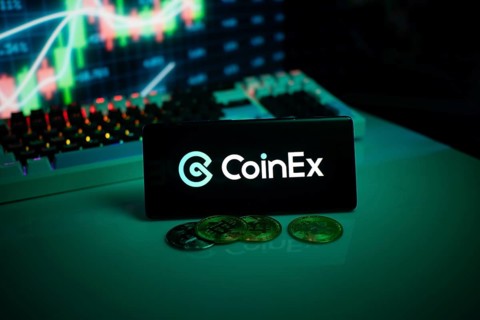 CoinEx logo displayed with coins on a desk and trading graphs in the background
