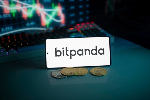 Bitpanda logo on white screen with coins and trading graphs in the background