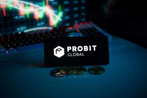 Probit Global logo with coins on a desk, against trading graphs backdrop