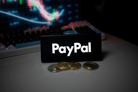 PayPal logo shown with coins and illuminated market analysis graph