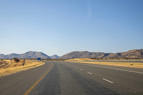 Scenic view of the open road between Windhoek and Outjo, surrounded by dry grasslands and distant
