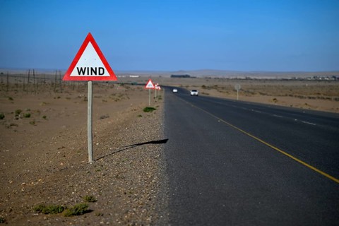 Caution wind sign on a road near Oranjemund, diamond restricted area, Karas region, Namibia