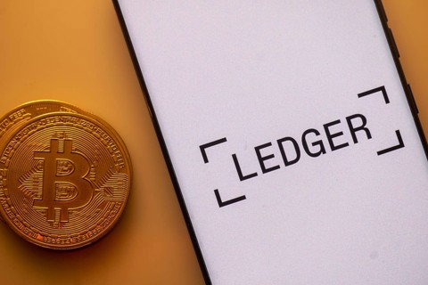 Bitcoin displayed next to a smartphone with Ledger app interface on white background
