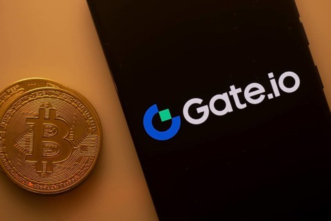 Bitcoin coin adjacent to a phone with the Gate.io logo on a black screen