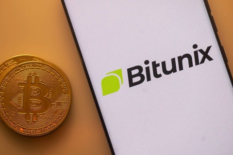 Bitunix app on phone screen next to a Bitcoin coin