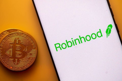 Robinhood logo displayed on a smartphone next to a Bitcoin coin