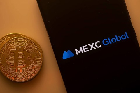 Bitcoin coin beside phone showing MEXC Global logo on a black background