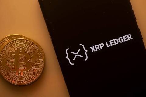 Bitcoin coin next to a phone displaying XRP Ledger logo on a black background