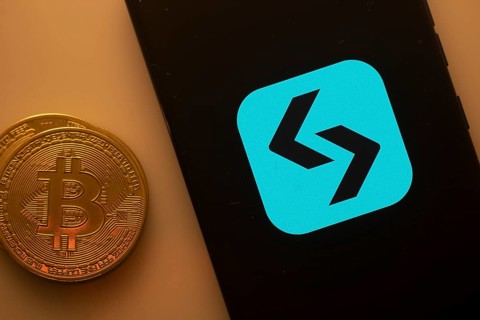 Unidentified logo on smartphone beside Bitcoin, emphasizing cryptocurrency and blockchain