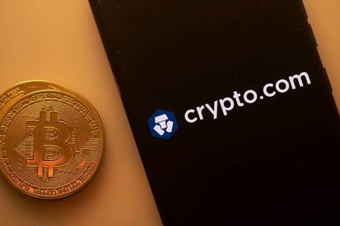 Bitcoin coin next to a phone with Crypto.com logo on black screen