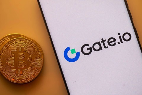 Gate.io logo on a smartphone screen next to a Bitcoin standing on an orange backdrop