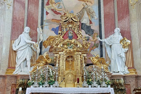 Magnificent baroque altar with golden details and statues, surrounded by ornate frescoes,