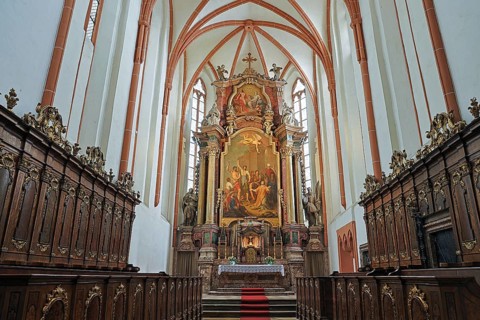 Magnificently designed church altar with rich wood carving and large painting in the background, St