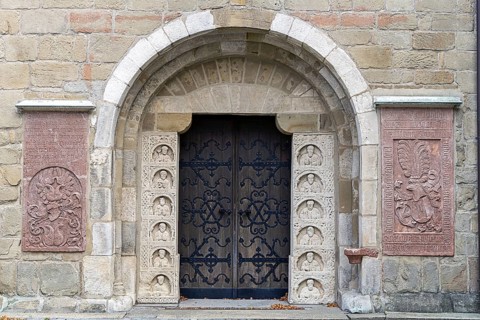 Historic stone door with reliefs and coats of arms, decorated medieval architecture, parish church