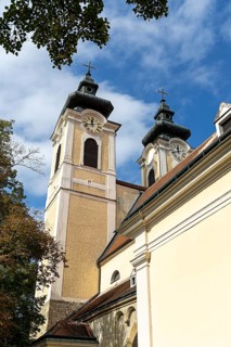 Baroque church towers with clocks rise against a clear blue sky in the afternoon light, St.Stephan