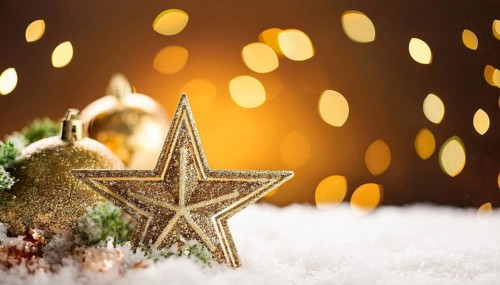 Golden christmas star and baubles creating a magical atmosphere on a snowy surface with warm bokeh