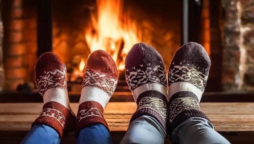 Couple relaxing with christmas socks by the fireplace on a cold winter evening, AI generated