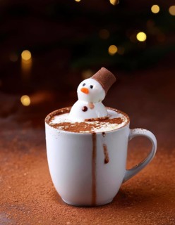 Delicious hot chocolate with funny marshmallow snowman melting on cocoa powder background with