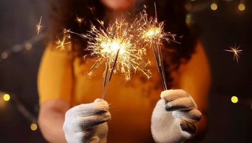 Woman wearing white gloves holding burning sparklers celebrating christmas eve, AI generated