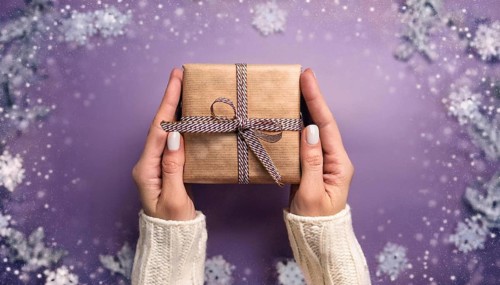 Woman holding christmas present with purple snowy background, AI generated